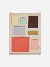 Set of colorful fabric pouches on a beige wall hanging